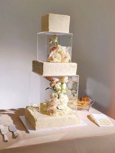 three tiered wedding cake with flowers on the top and bottom, sitting on a table