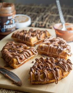 several waffles with chocolate drizzled on them sitting on a cutting board