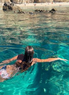 a woman is swimming in the water near rocks