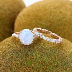 an opal and diamond ring sitting on top of moss