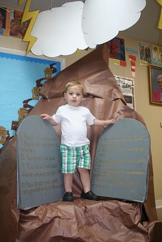 a young boy standing on top of a giant paper boat in a room with posters above it