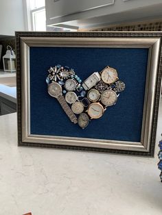 a heart made out of watch pieces in a frame on a counter top next to a window