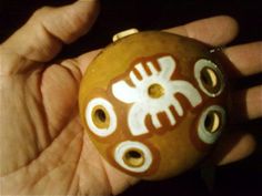 a hand holding a brown and white bead with holes in it's center