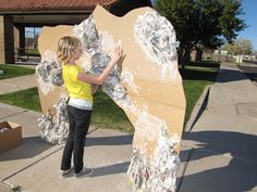 a woman standing next to a giant piece of paper mache in front of a building