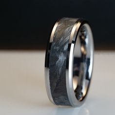 a wedding band with a black and white marble inlay is shown on a table