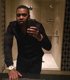 a man taking a selfie in front of a bathroom mirror with his cell phone