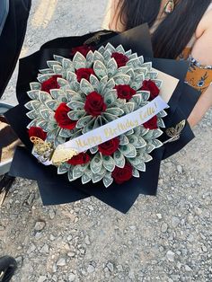 a woman holding a bouquet of roses and money wrapped in paper with the words happy birthday written on it