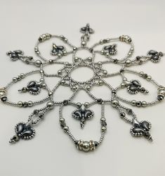 a snowflake made out of silver beads and other metal objects on a white surface