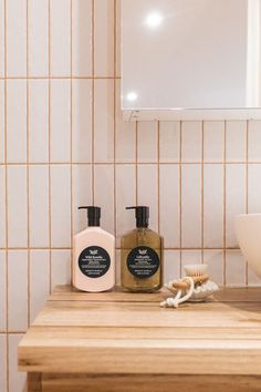 a bathroom counter with two soaps and a brush on it next to a mirror