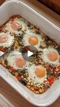 an egg dish in a white casserole dish on a wooden table with a spatula