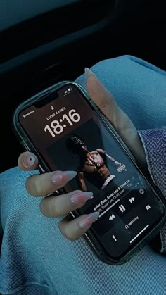 a woman is holding her cell phone while sitting in the back seat of a car