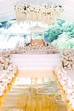 an outdoor wedding setup with flowers on the ground and tables set up in front of it