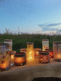 many jars with candles are sitting on a table