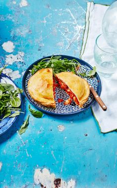 a blue plate topped with a cut in half sandwich next to salad and water glasses