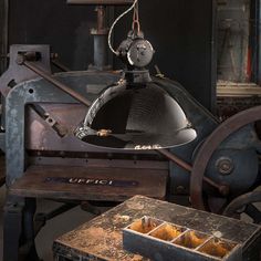 an industrial lamp hanging from the ceiling next to some boxes and other items in front of it