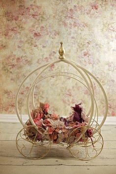 a flower arrangement sitting on top of a white stand in front of a floral wallpaper