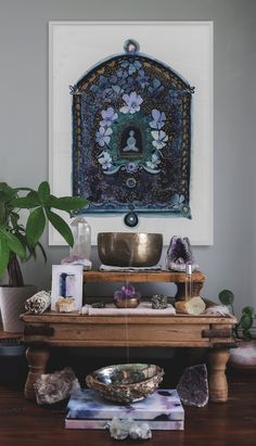 a wooden table topped with lots of clutter next to a wall mounted art piece