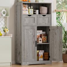 a wooden cabinet with two doors and shelves on the side in a room next to a potted plant