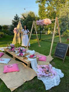 a woman standing in front of a table with flowers on it and pink napkins