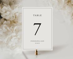 a table number card with white flowers in the background