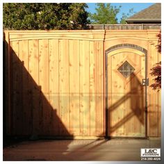 the shadow of a person standing in front of a wooden fence with a gate on it