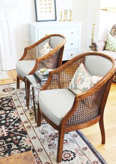 two wicker chairs sitting on top of a rug in a living room next to a fireplace