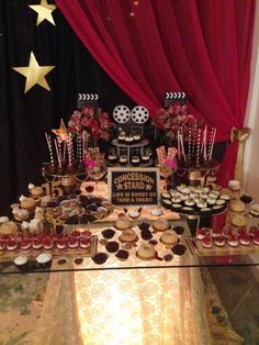 a dessert table filled with cupcakes and pastries on top of a table