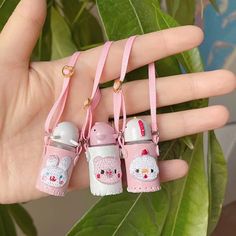 three baby bottles are being held in the palm of someone's hand with pink straps