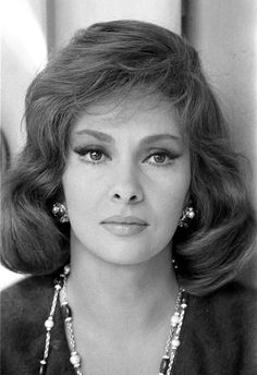 an old black and white photo of a woman with long hair wearing pearls on her necklace