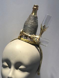 "Champagne Fascinator- bottle headpiece- celebrate- New Years- I love champagne-Kentucky derby- Derby days Hello,      This fascinator headband has a beaded champagne bottle and 2 gold champagne glasses with some glitter. It's perfect for a birthday celebration, NYE, holiday party and makes a great conversion piece.    It's placed in a 1/2\" matching covered headband that's adjustable and very comfortable. --------------------------------------------------- To return to my shop: https://www.etsy Derby Hats Diy Ideas, Gold Champagne Glasses, New Years Eve Tops, Derby Outfits, Mannequin Art, Parade Float, Fascinator Headband, Gold Champagne