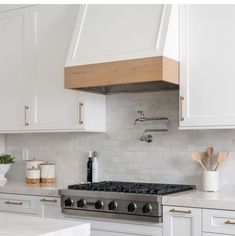 a stove top oven sitting inside of a kitchen next to wooden spoons and utensils