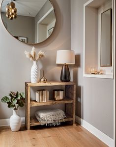 a mirror and some vases on a shelf in a room with wood flooring