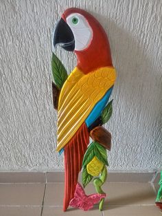 a colorful parrot statue sitting on top of a tile floor next to a planter