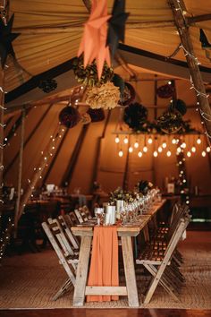 the inside of a tent with tables and chairs set up for a wedding reception in orange napkins