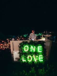 a man standing in front of a sign that says one love on it at night