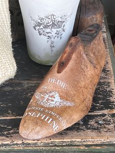 an old wooden shoe sitting on top of a table next to a potted plant