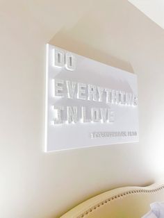 there is a sign that says do everything in love on the wall above a bed