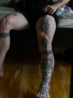 a tattooed man sitting on top of a wooden floor