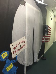 a room with a sign that says welcome to earthlings and an american flag on the wall