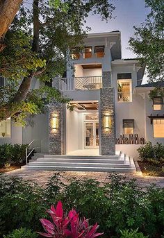 a large white house with steps leading to it's front door and trees in the foreground