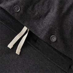 a close up view of the zipper on a jacket with buttons and white string attached to it