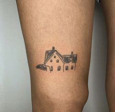 a woman's leg with a small house tattoo on the side of her thigh