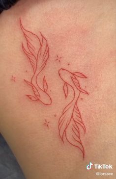 the back of a woman's shoulder with two goldfish tattoos on her left side