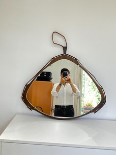 a man taking a selfie in front of a mirror on top of a dresser