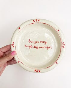 a hand holding a white plate with red writing on it that says, i love you every single day and night