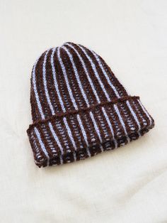 a brown and white knitted beanie sitting on top of a white cloth covered table