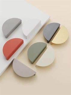 several different shapes and sizes of circular objects on a white surface with beige, gray, red, yellow, and green colors