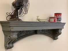 an old fan is sitting on top of a shelf next to a can of paint