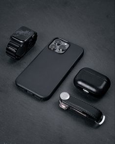 an iphone case and other accessories are laid out on a black surface, including a watch