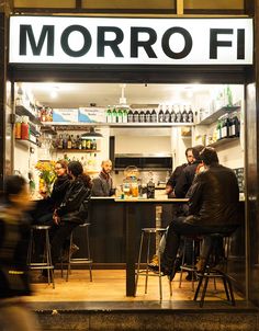 people sitting at tables in front of a bar with the word morro fi written on it